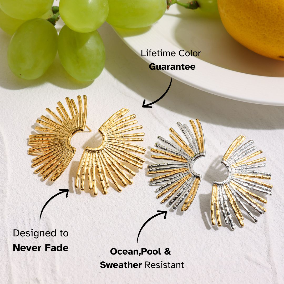 Bold gold sunburst earrings on white background, styled with grapes and lemon
