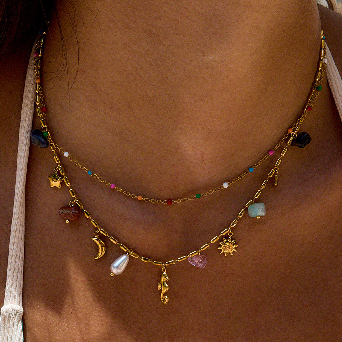 Gold necklace with various charms on a person's neck