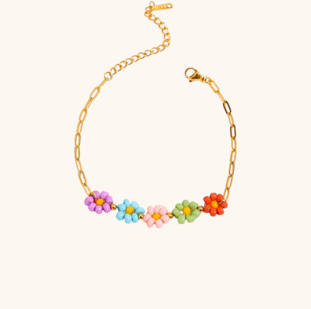 Colorful flower beaded bracelet on gold chain, laid flat with pink flowers