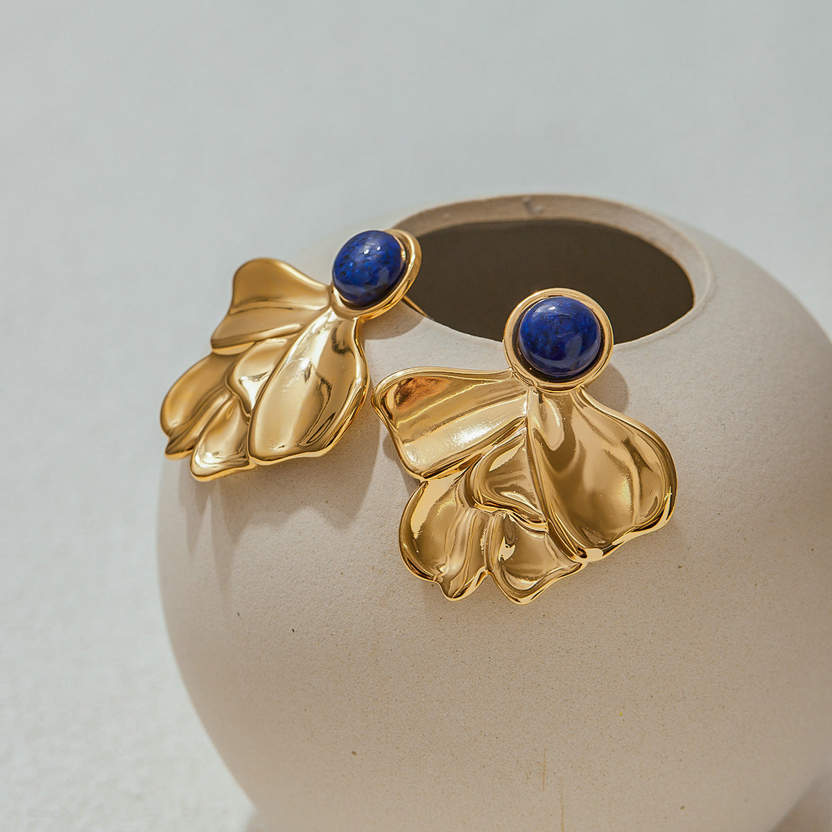 Unique artistic earrings displayed with ceramic vase