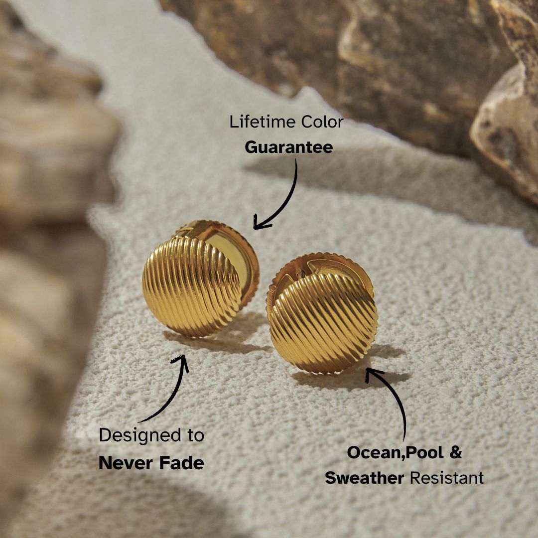 Vintage-style ribbed gold clip-on earrings on textured beige stone