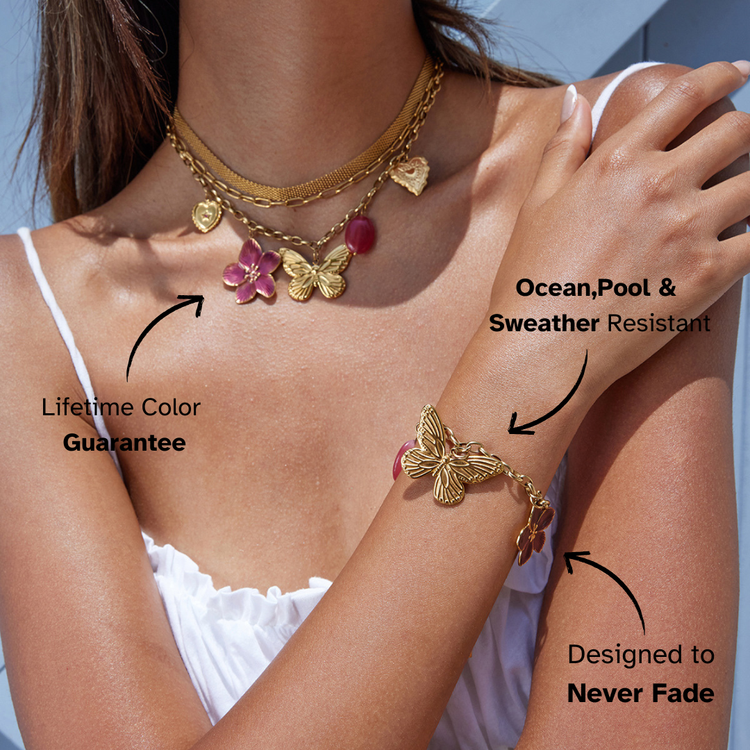 Model wearing layered gold charm necklace with butterfly and flower pendants
