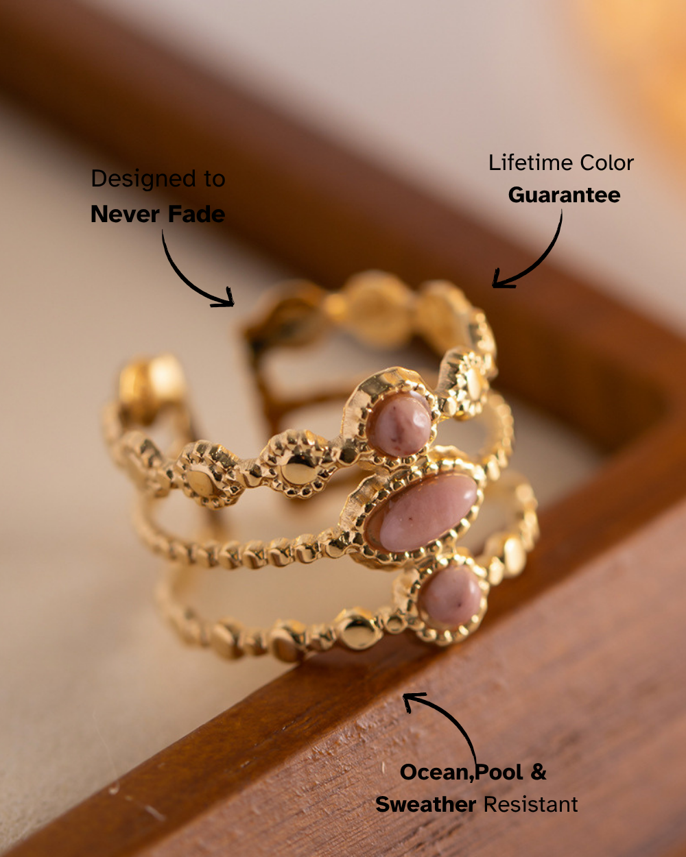 Gold ring with pink stones on a wooden surface, featuring text about durability and features.