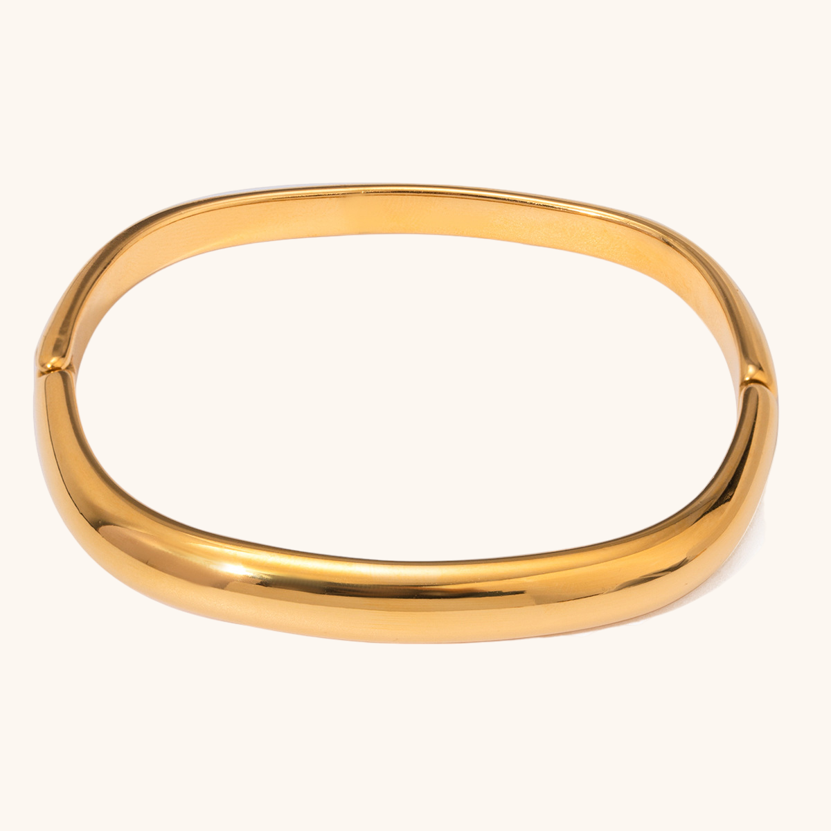 Minimalist oval gold bangle bracelet displayed on a clean beige background