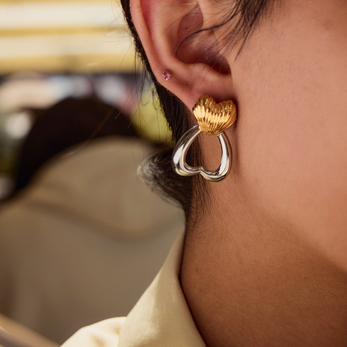 Close-up of the earrings worn on-ear, showing gold top and silver loop
