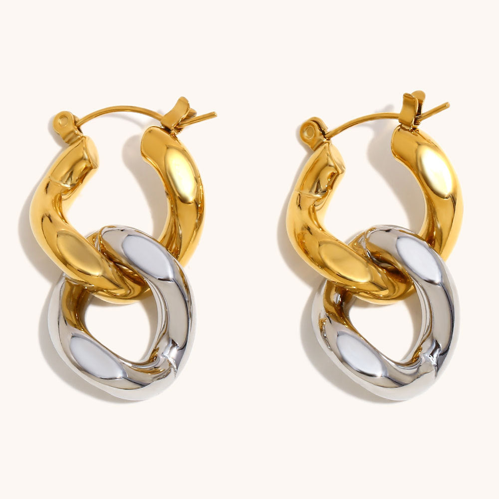Sculptural gold hoop earrings with silver link detail lying flat
