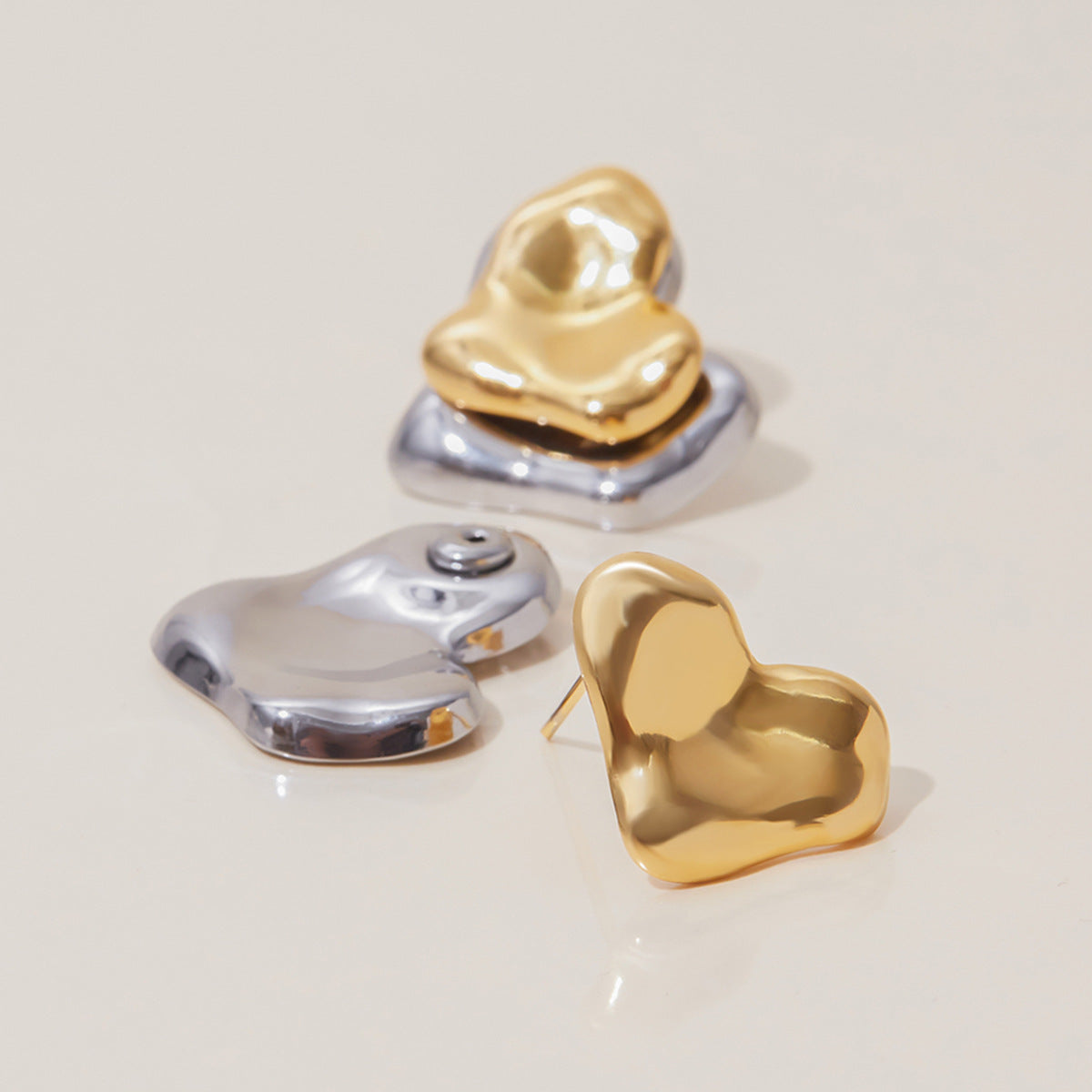 Close-up of gold and silver heart-shaped earrings with high-shine finish