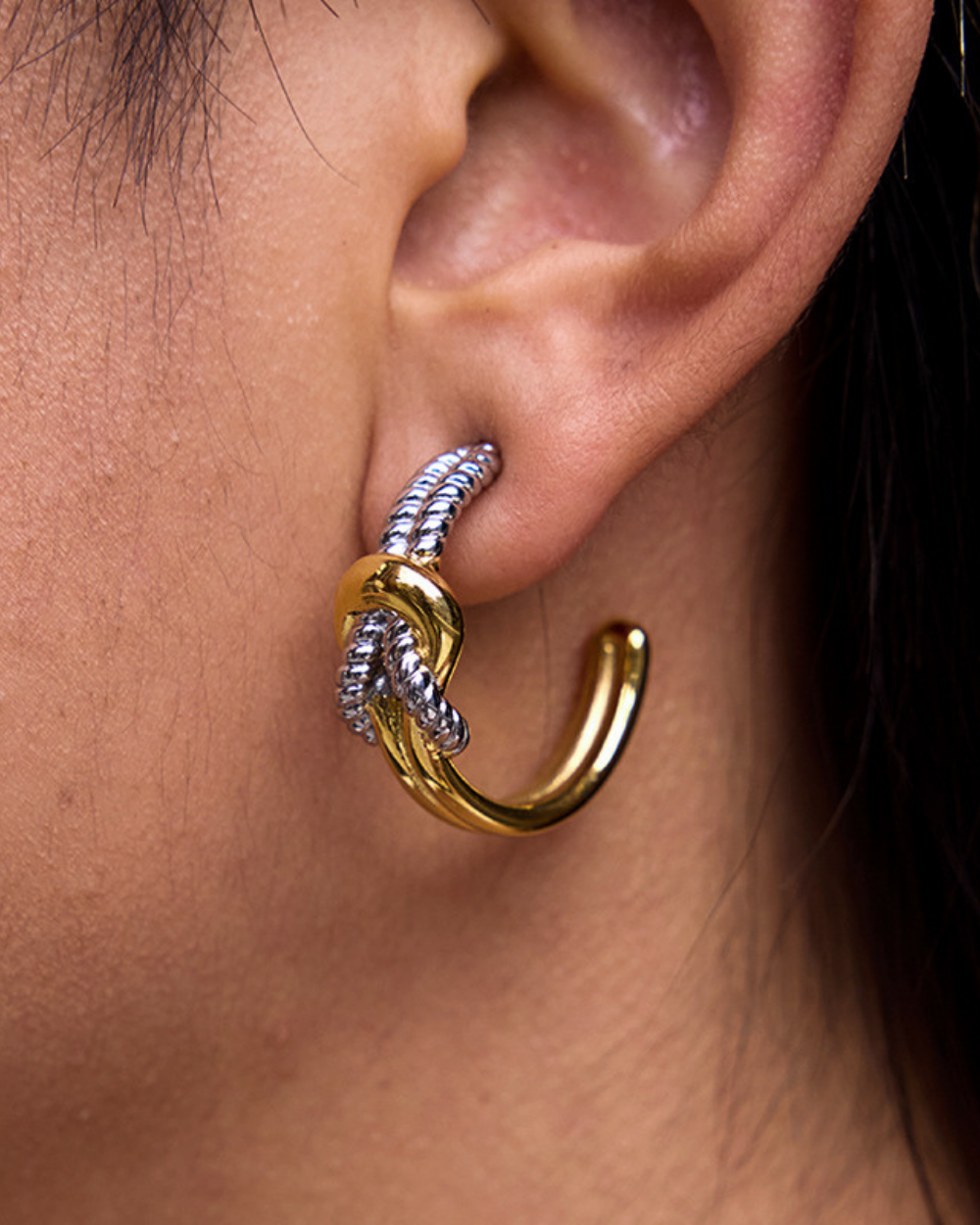 Gold and silver hoop earring worn on an ear