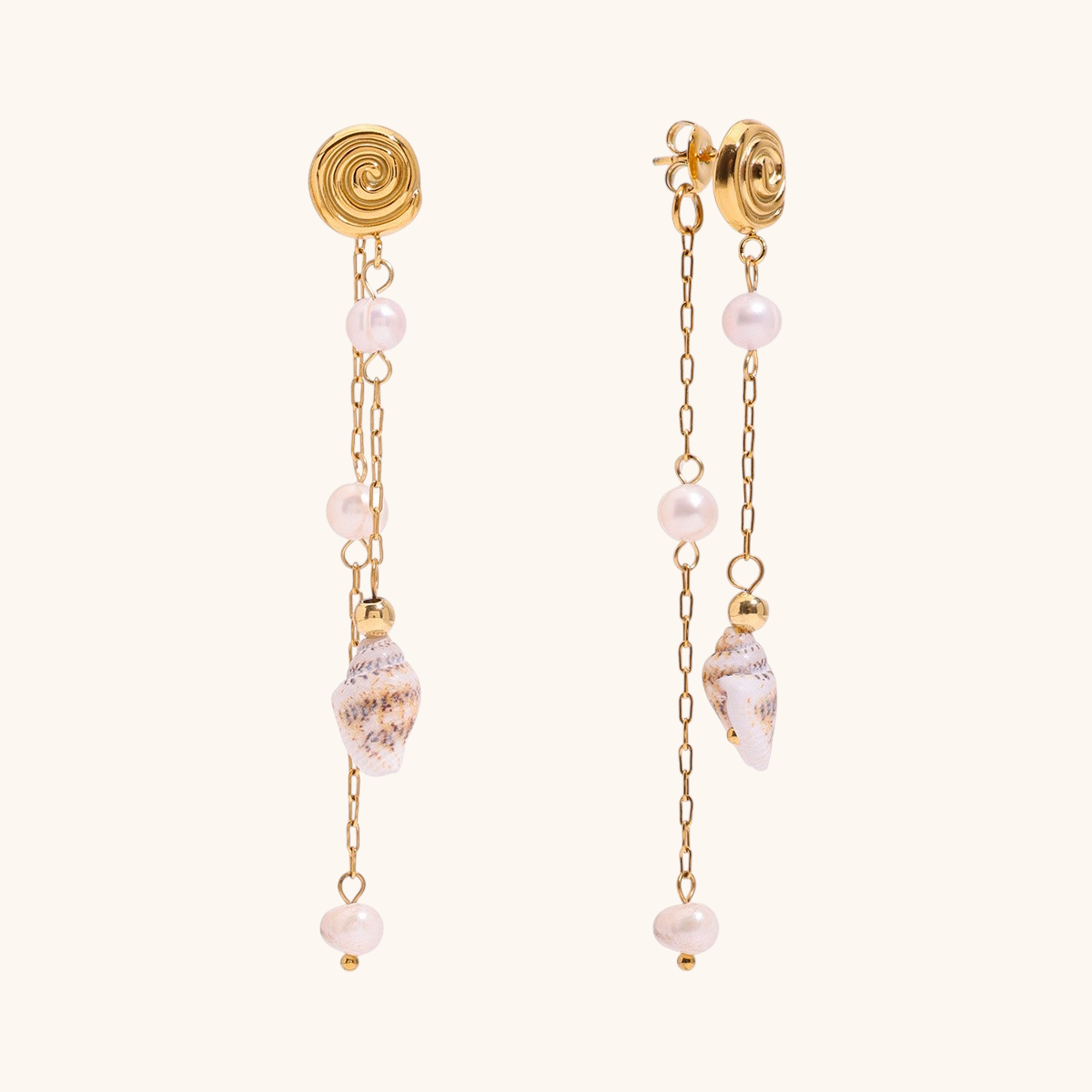 Long gold drop earrings with pearls and shell charms, laid beside photos and sunglasses.