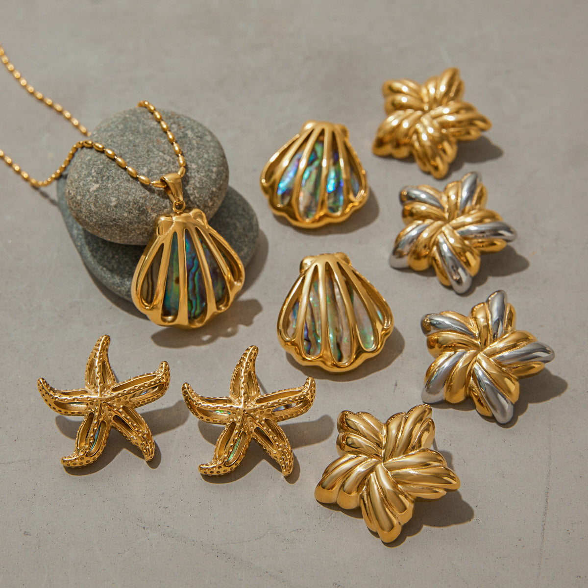 Coastal-themed gold necklace and earrings arranged with natural rock background