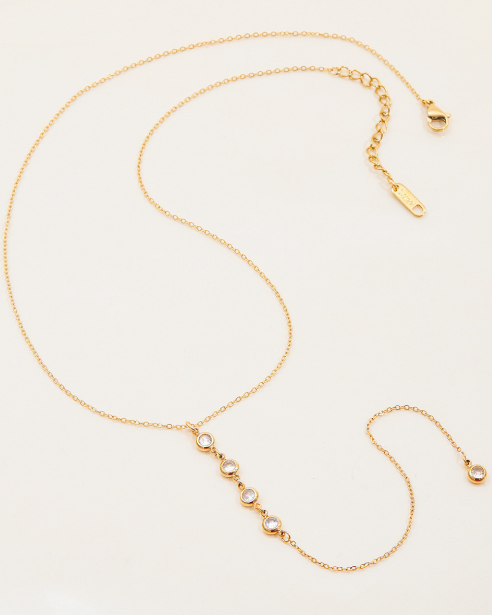 Gold necklace with small round beads on a light beige background