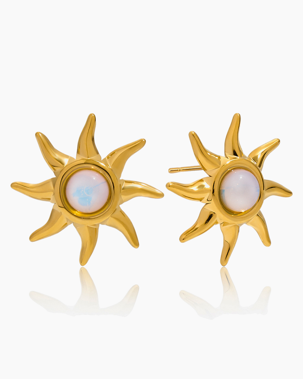 Gold sun-shaped earrings with a central gemstone on a white background