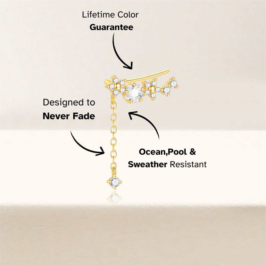 Asymmetric gold ear cuff with long dangle chain and zircon stones, close-up view