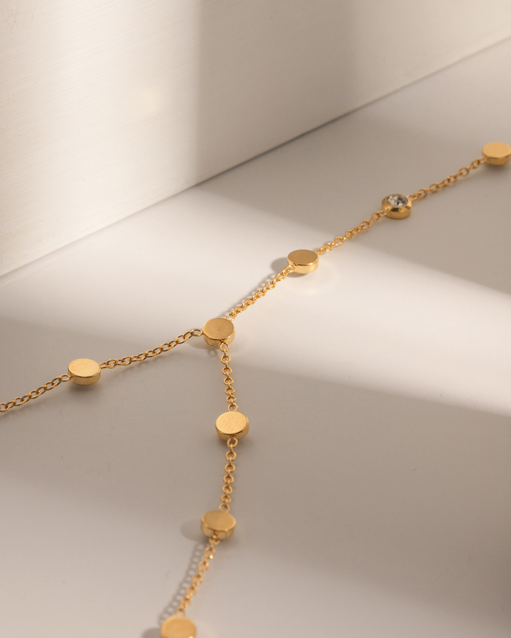 Gold necklace with round pendants on a light background