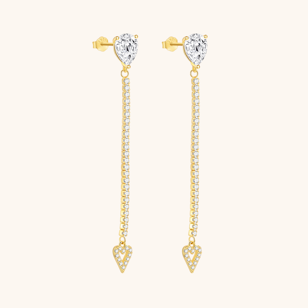 Close-up of long heart-shaped drop earrings with pear-cut stud and crystal detailing, worn with blonde hair