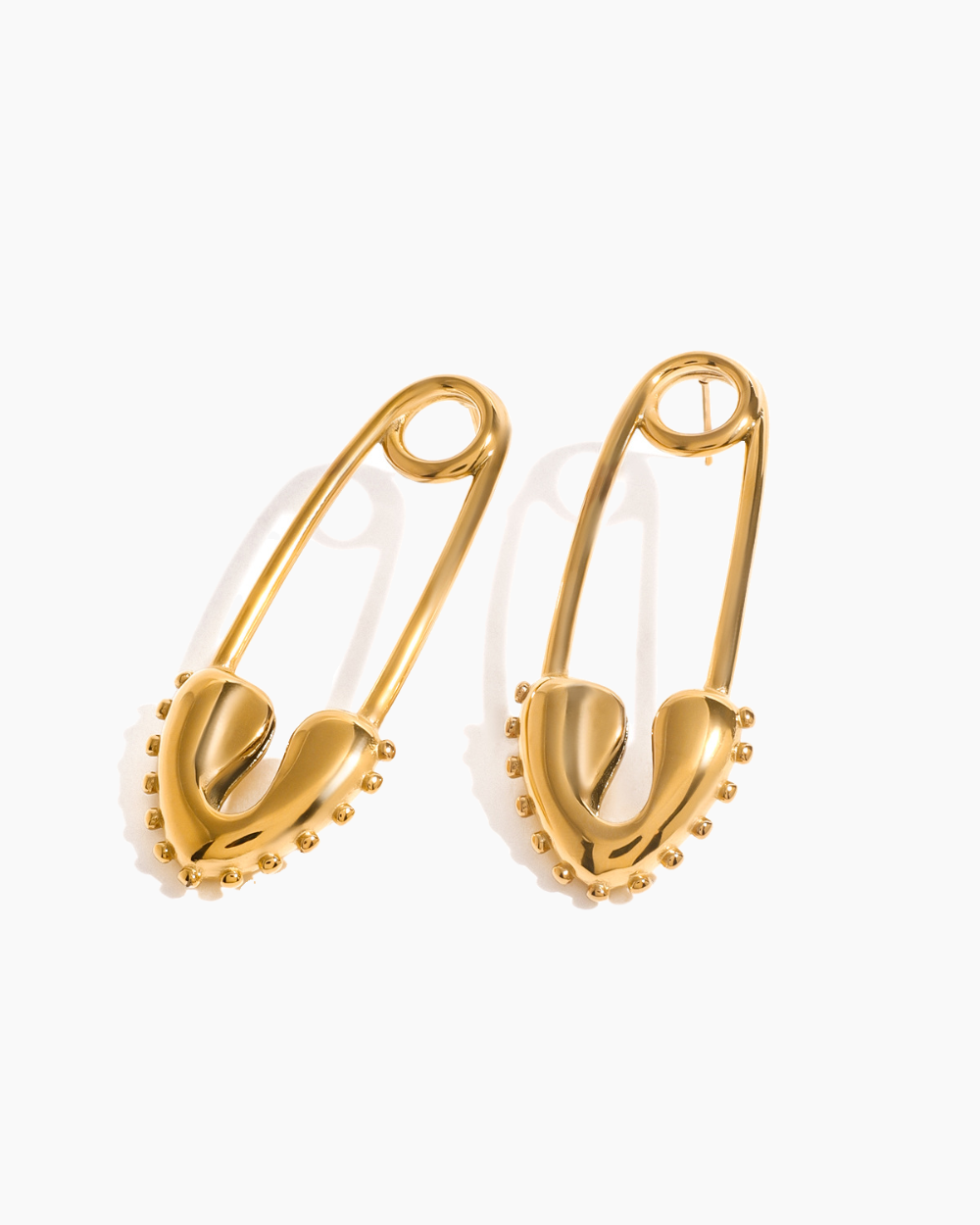 Gold safety pin earrings on a white background