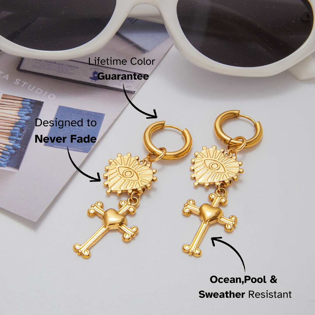 Gold earrings with religious designs on a light gray background, featuring text about color guarantee and water resistance.