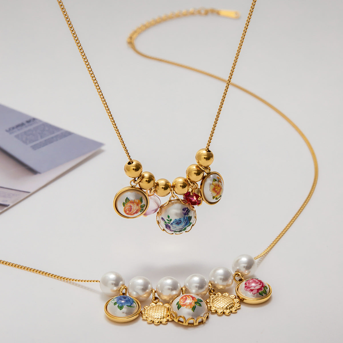 Gold necklace with floral-themed charms on a light background