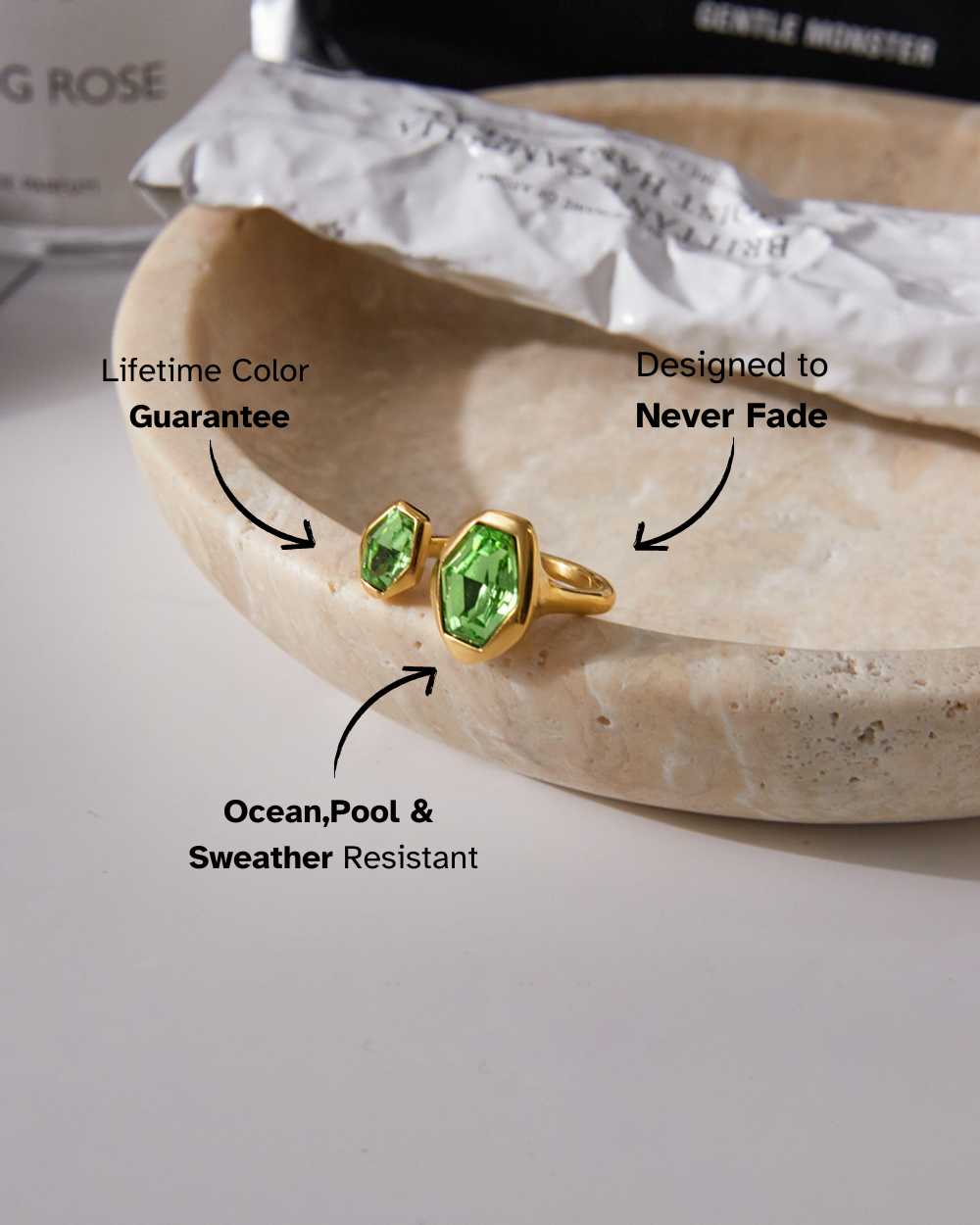 Gold earrings with green gemstones on a stone surface, featuring text about product guarantees.