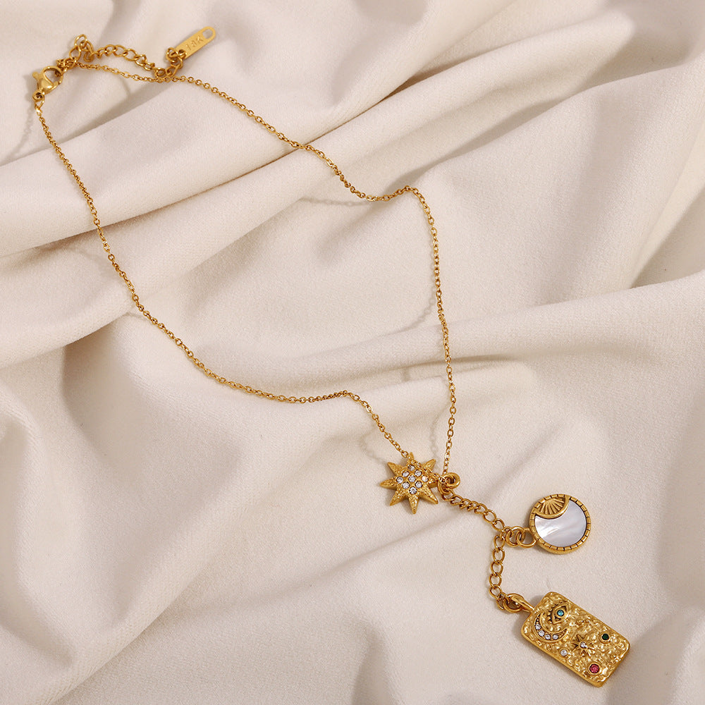 18K gold star moon necklace with textured rectangular charm on soft fabric backdrop