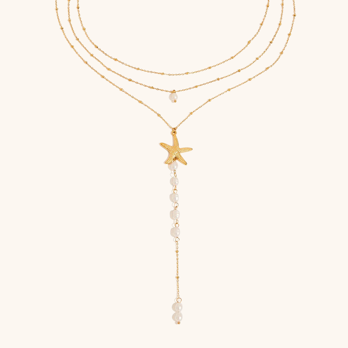 Close-up of starfish pendant and pearl strand layered necklace on neutral background