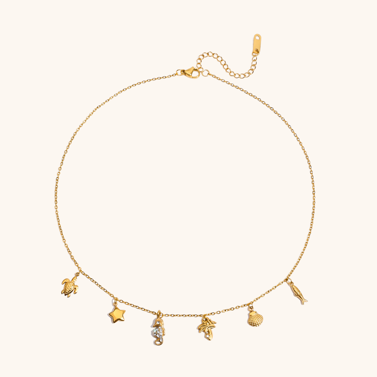 Close-up of gold necklace with marine animal pendants on white backdrop