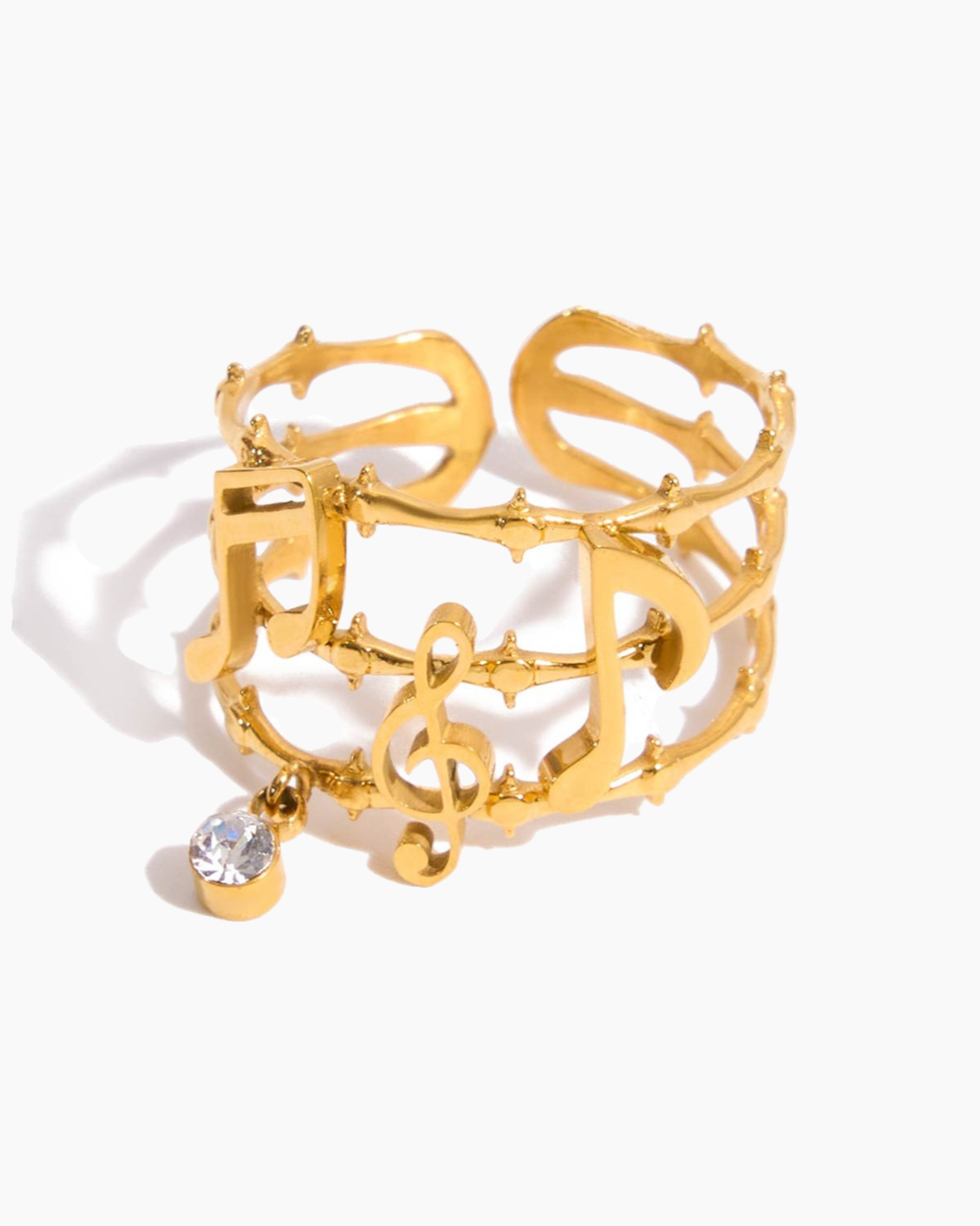Gold bracelet with musical notes and a clear gemstone on a white background