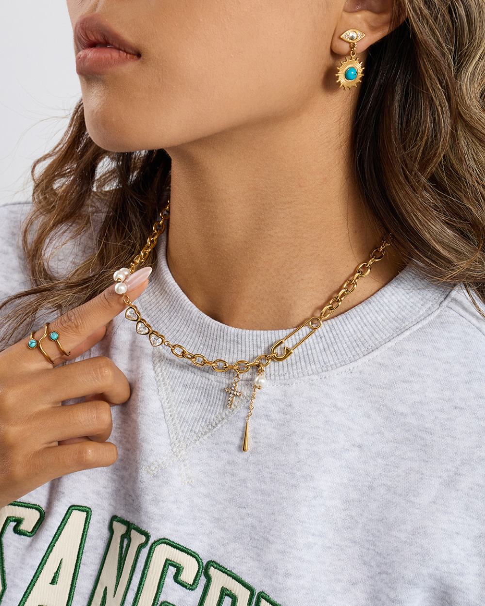 Close-up of a person wearing gold chain necklaces and earrings on a white background