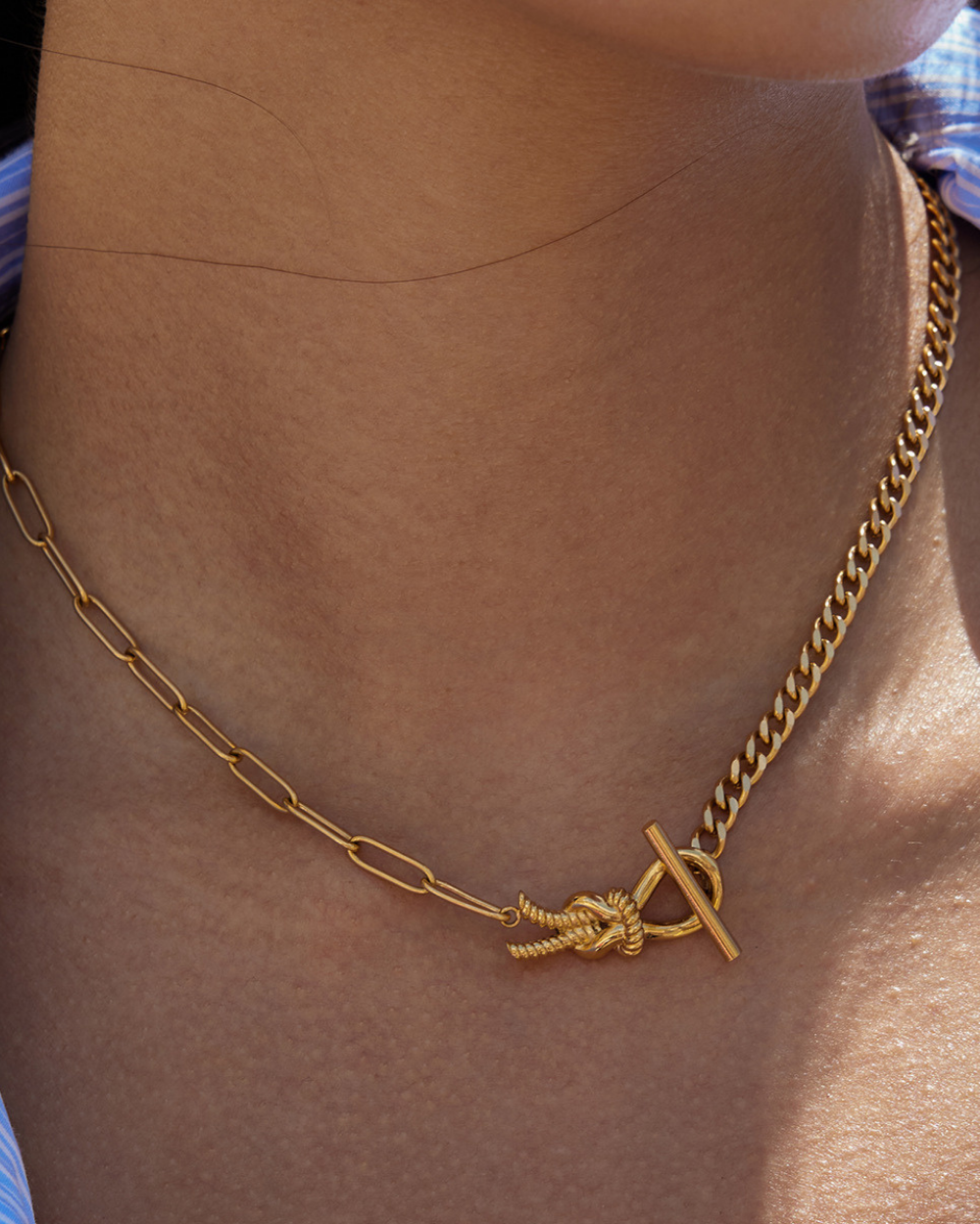 Gold chain necklace with a knot design on a person's neck