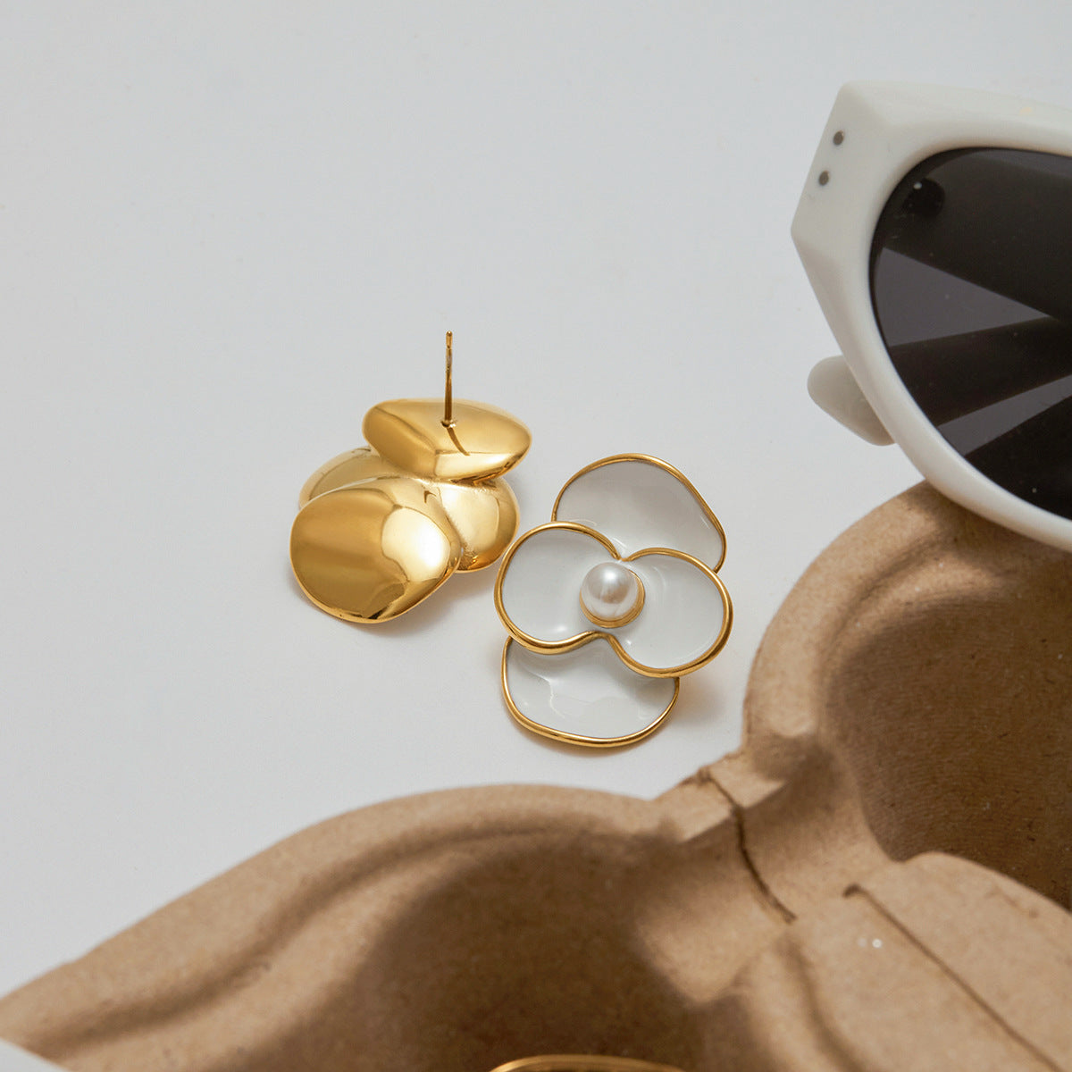 Statement white floral stud earrings worn with sunhat outdoors