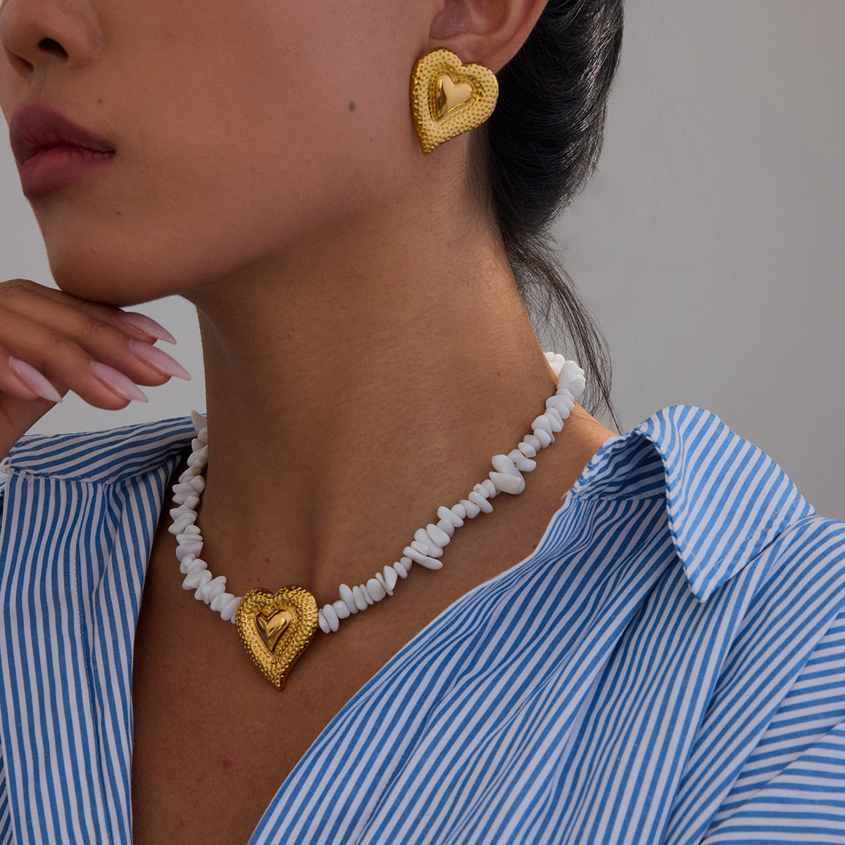 Woman wearing large gold heart earrings with striped shirt, lifestyle scene