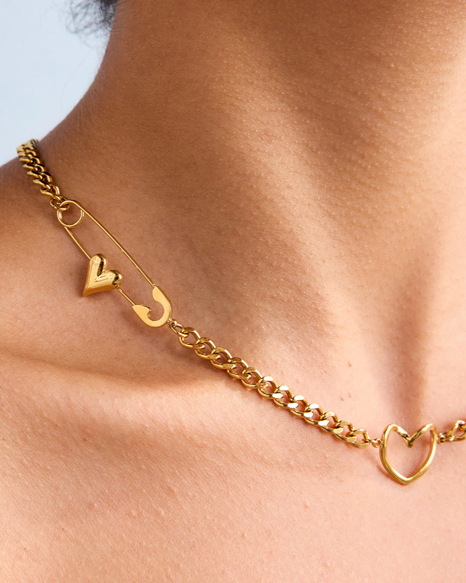 Model wearing safety pin heart necklace with white swimwear by the pool