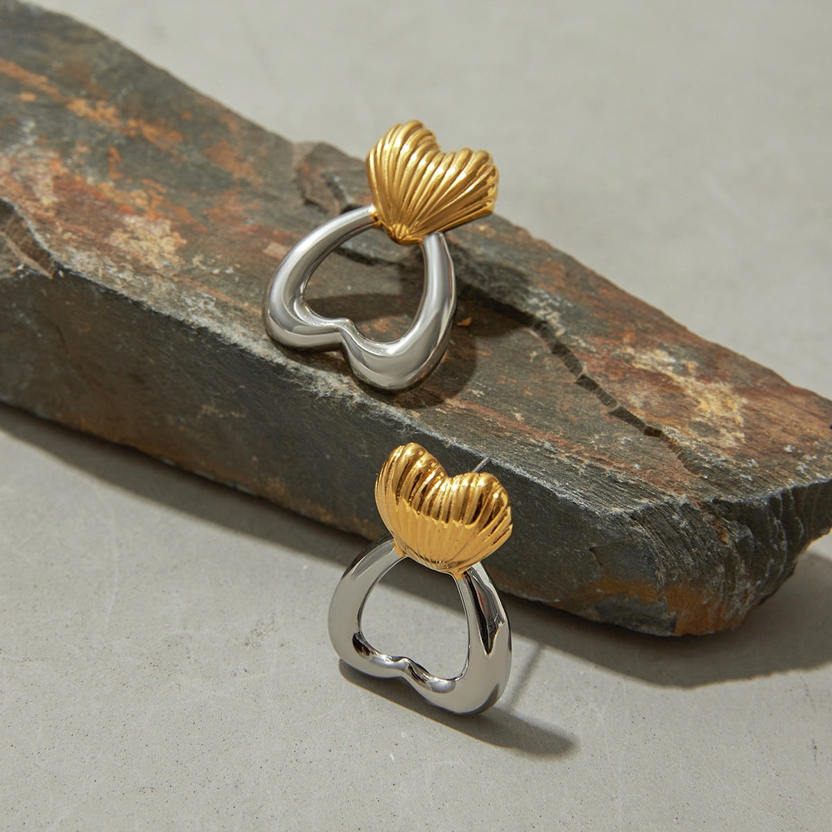 Artistic flat lay of sculpted heart earrings on grey stone
