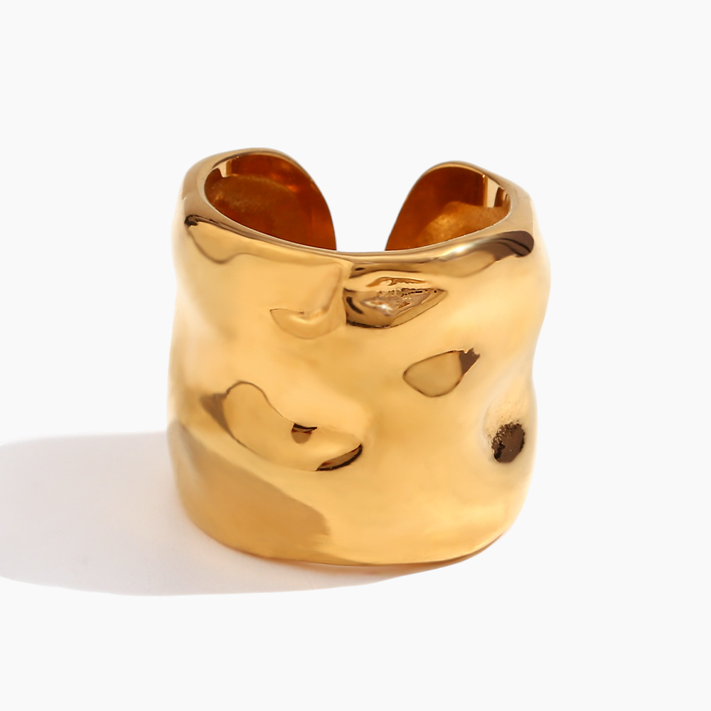 Gold ring with a face design on a white background
