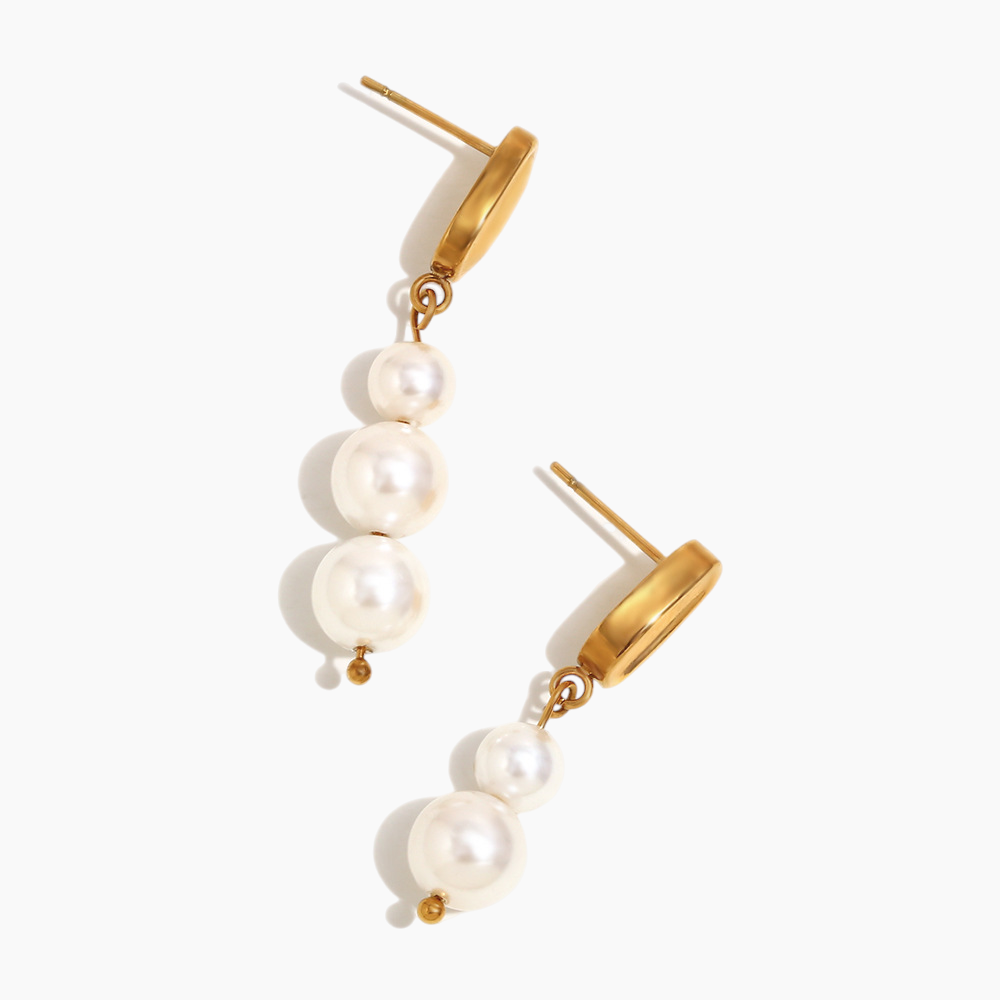 Statement pearl drop earrings displayed on neutral fabric background