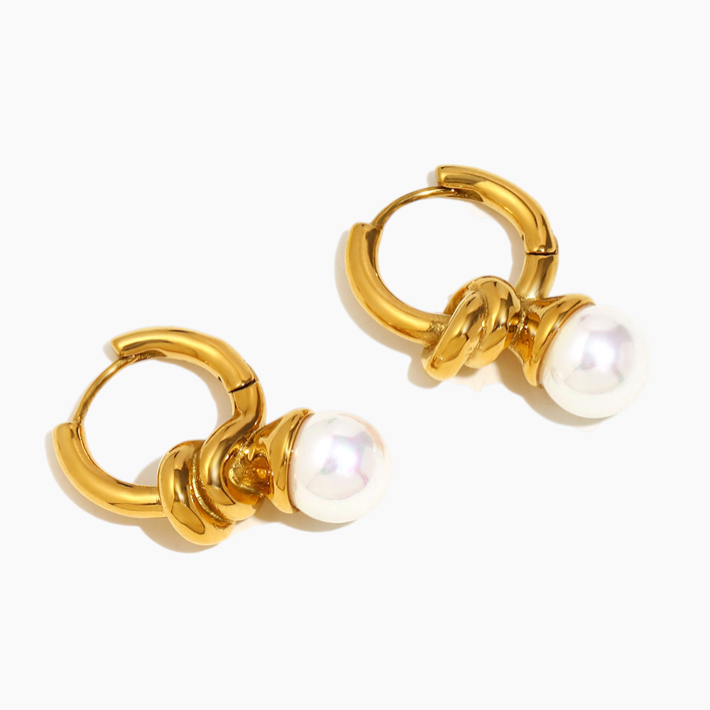 Flat-lay of statement pearl knot hoops on neutral linen background
