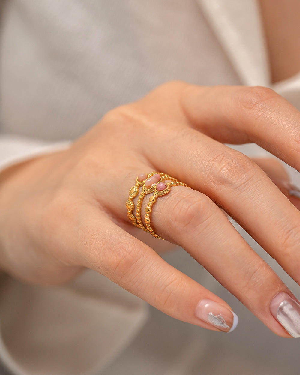 Hand wearing a gold ring with a blurred background