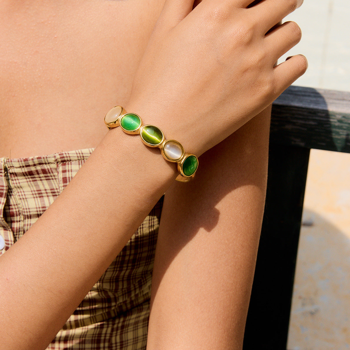 model wearing a green and white open cuff bracelet with gold rimmed stones
