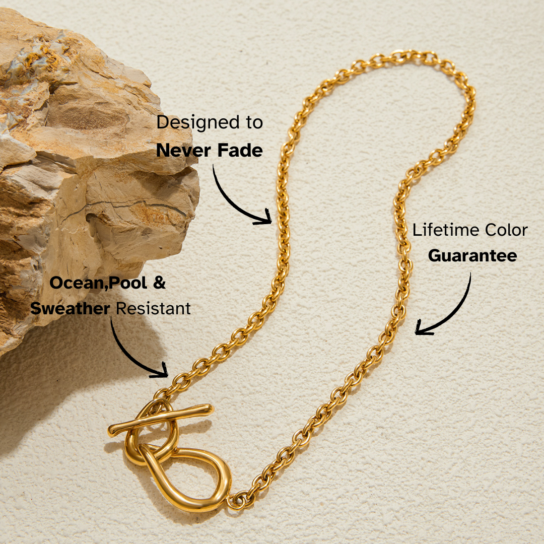 Gold chain necklace with text on durability and color guarantee against a beige background