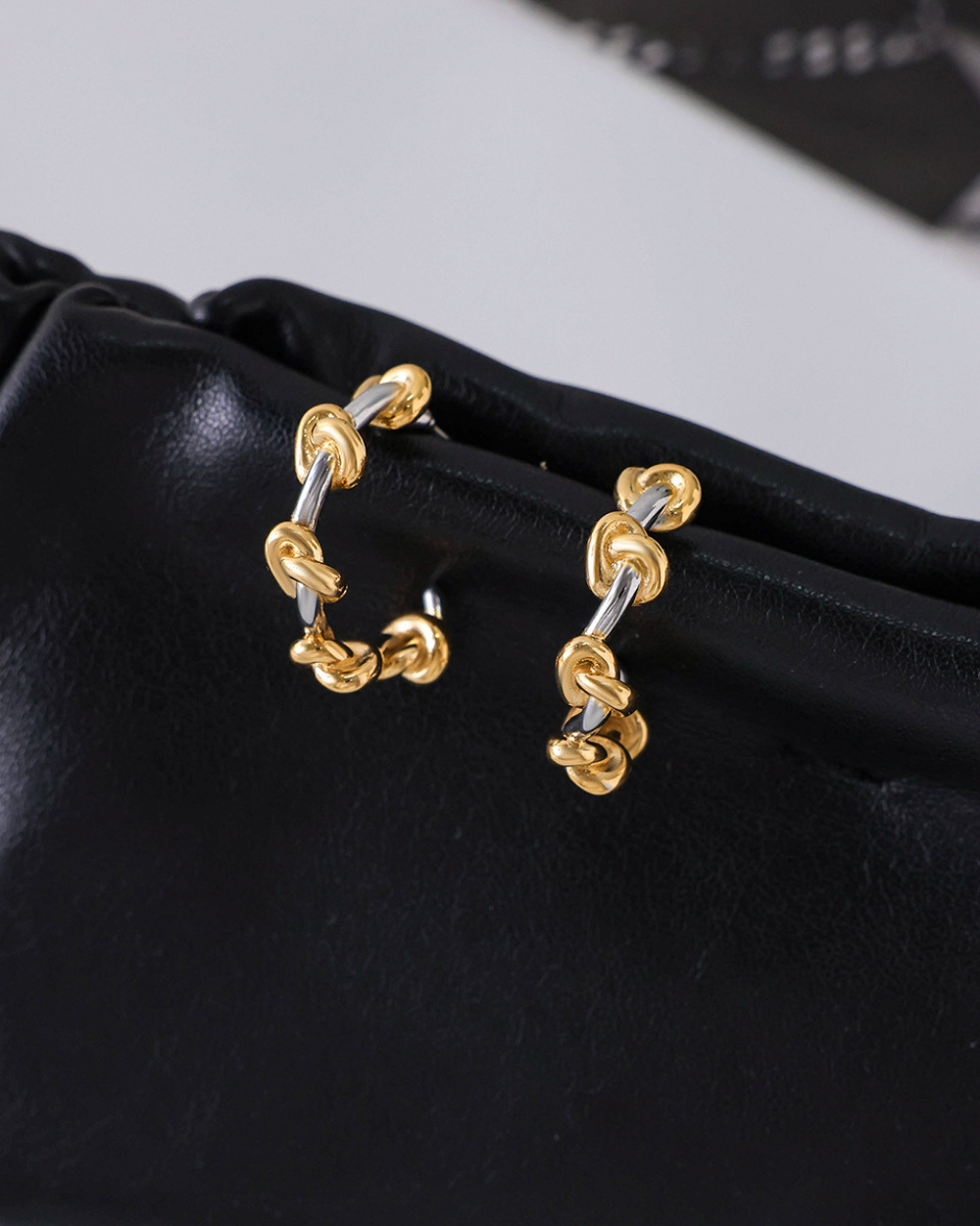 Gold and silver hoop earrings on a black surface