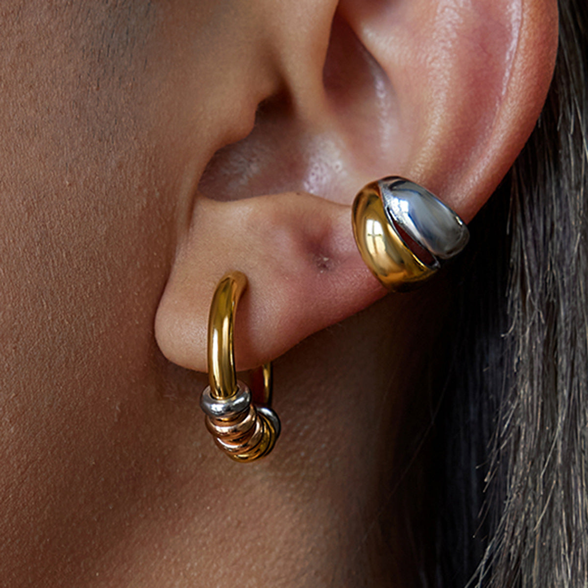 Close-up of tri-color hoop earrings on ear