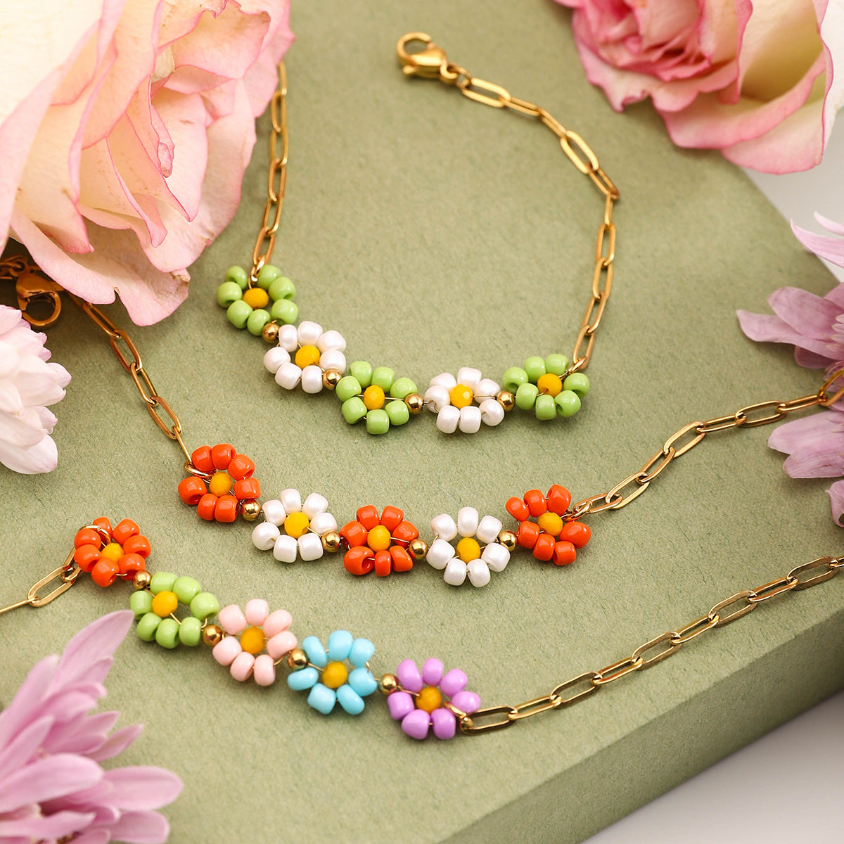 Set of three daisy bead chain bracelets styled with fresh flowers, pastel tones