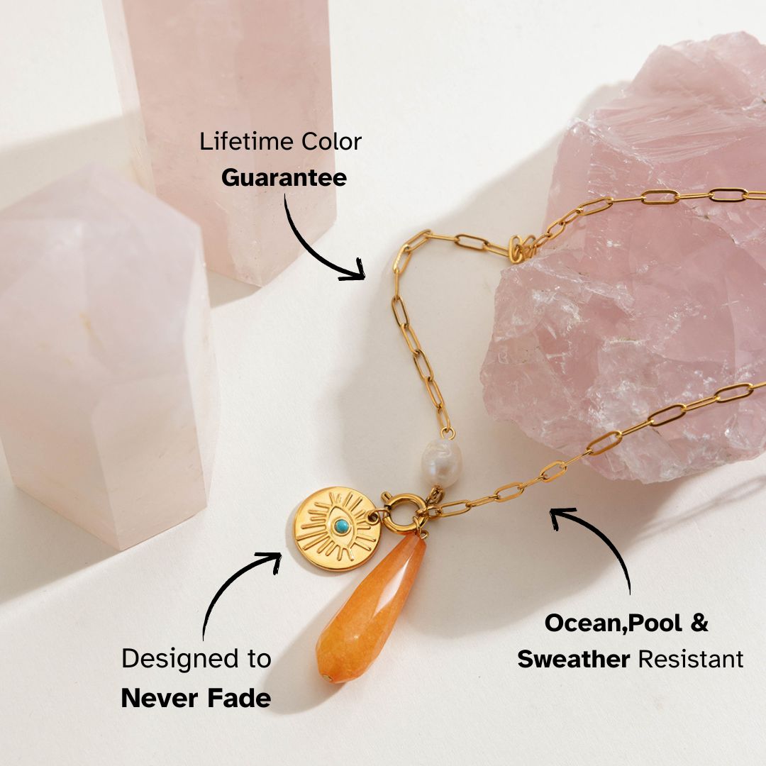 Layered gold necklaces styled with sunset-inspired teardrop pendant under sunlight