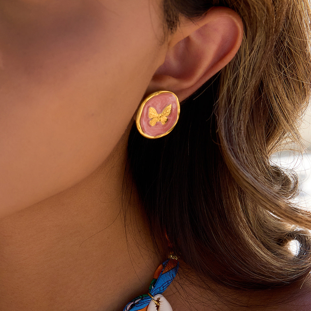 Close-up of pink and gold butterfly earrings on ear