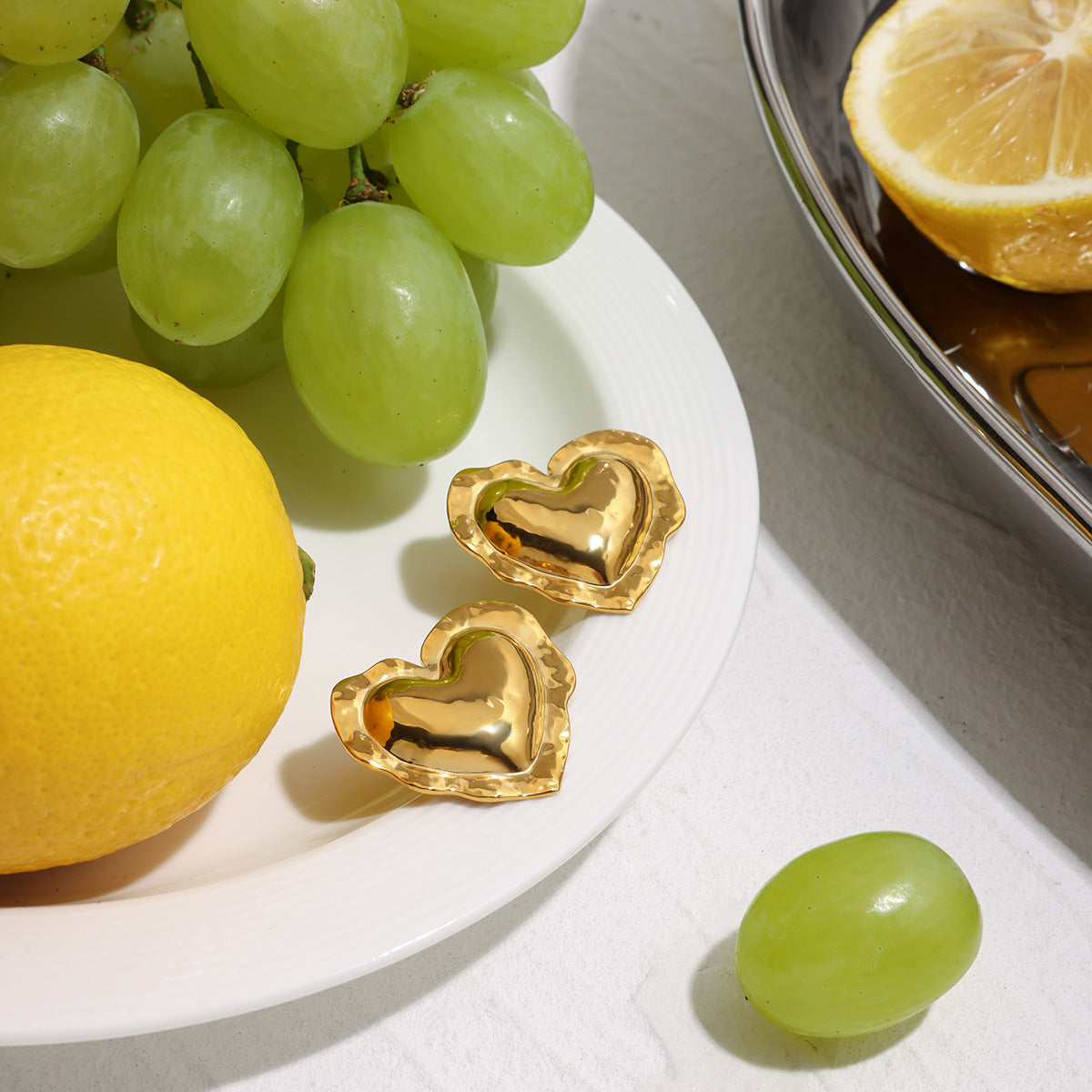 All-gold hammered heart-shaped earrings with shiny texture on ceramic plate