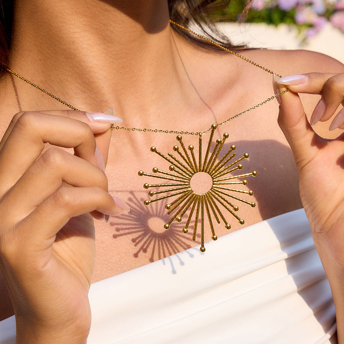 hand holding statement gold necklace under sunlight