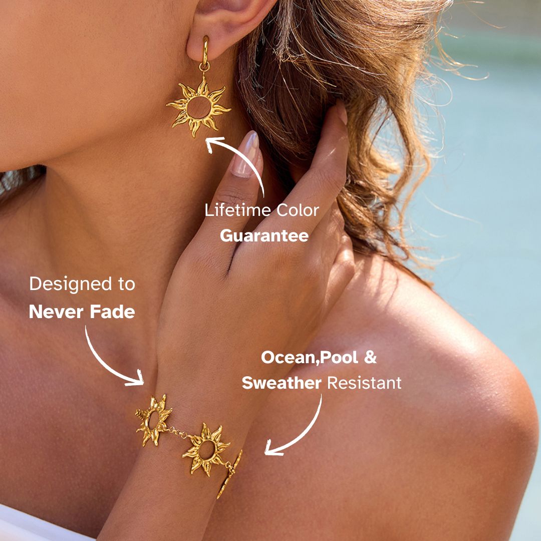 Close-up of a woman wearing a gold sun charm bracelet and matching earrings on the beach