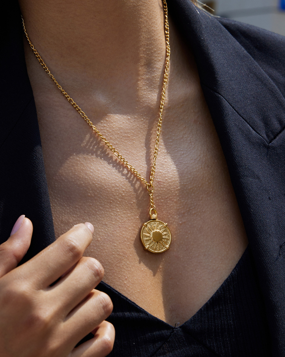 Gold necklace with a pendant worn by a person, with a blurred background