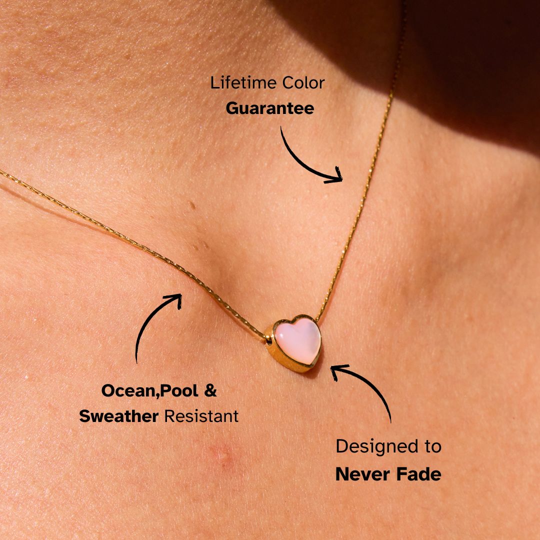 Model wearing gold necklace with pink heart pendant in the sun