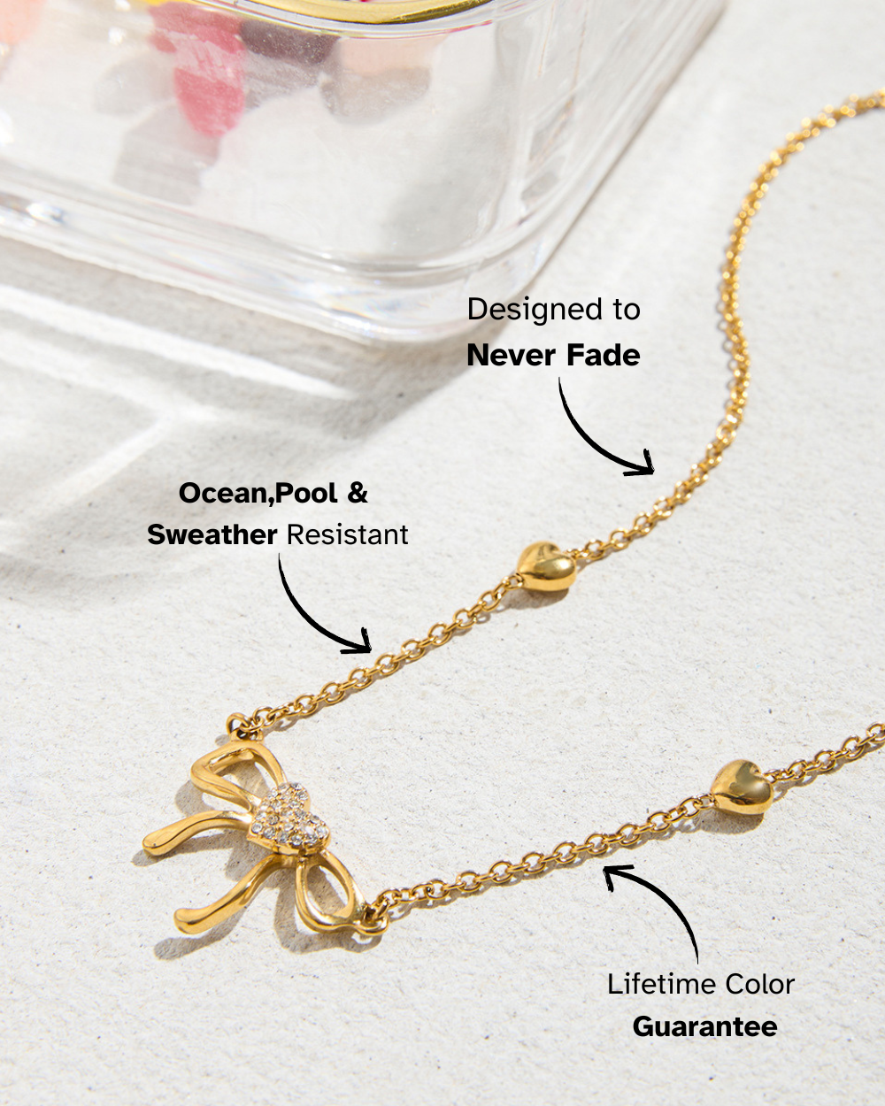 Gold necklace with bow design on a white background, featuring text about water resistance and color guarantee.
